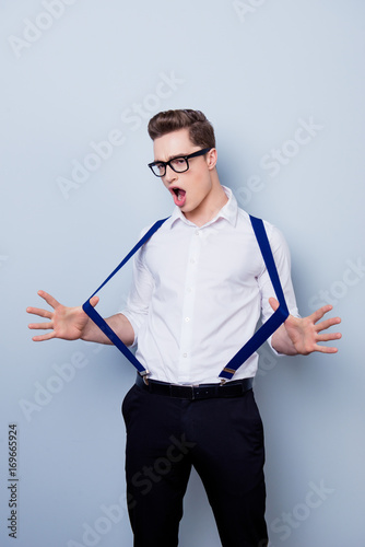 Vertical photo of attractive young playful flirty excited man in spectacles dressed in formal-wear pulling his suspenders photo