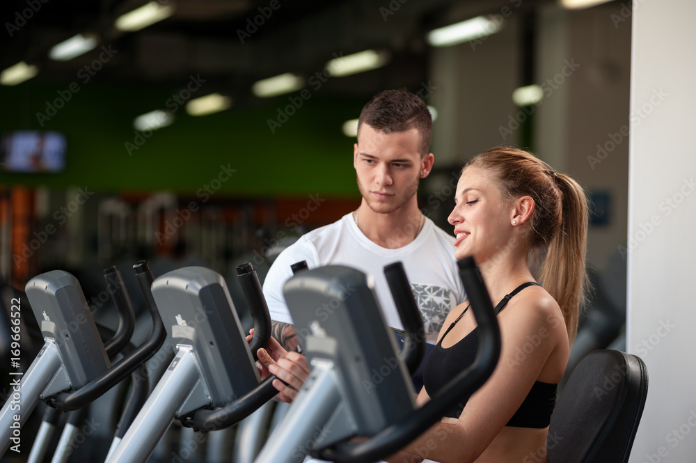 Young male coach with female client in gym