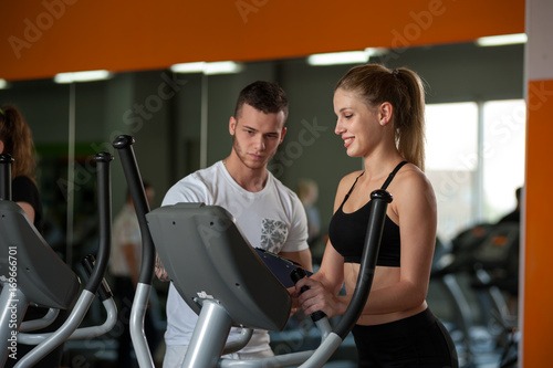 Personal trainer working with female client in gym