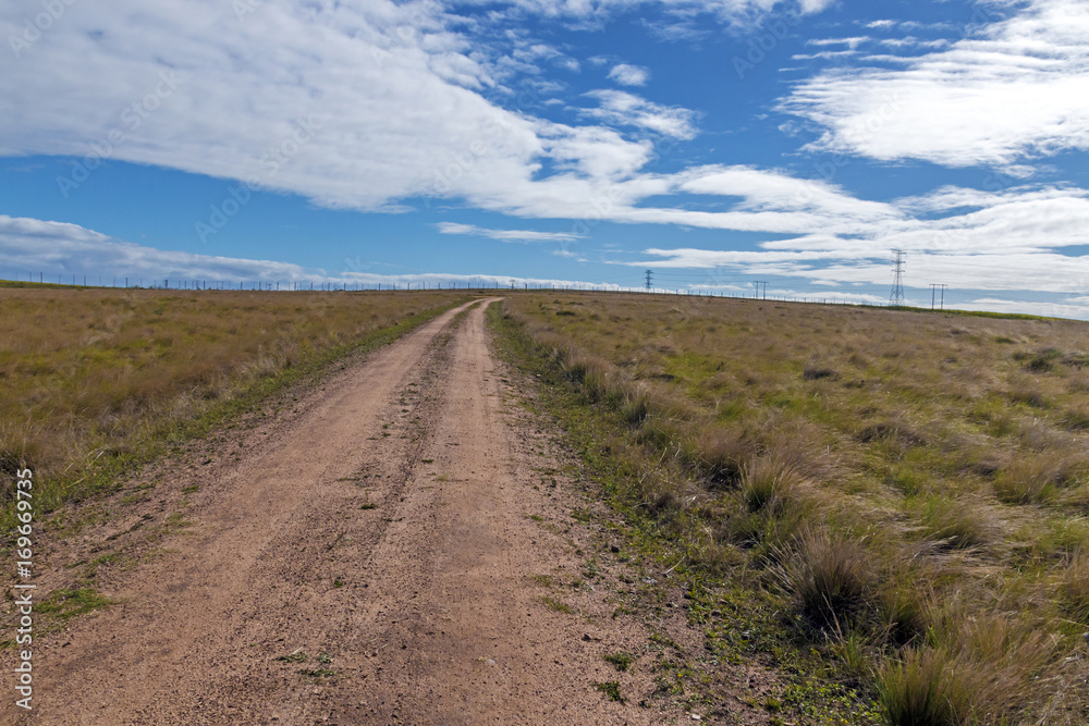 Empty Rural Dirt Road Leading Through Dry Winter Grassland