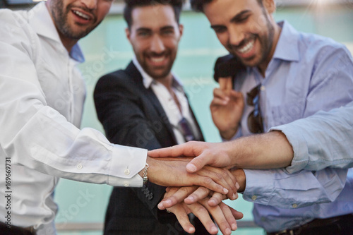 Three businessmen holding hands together in unity gesture