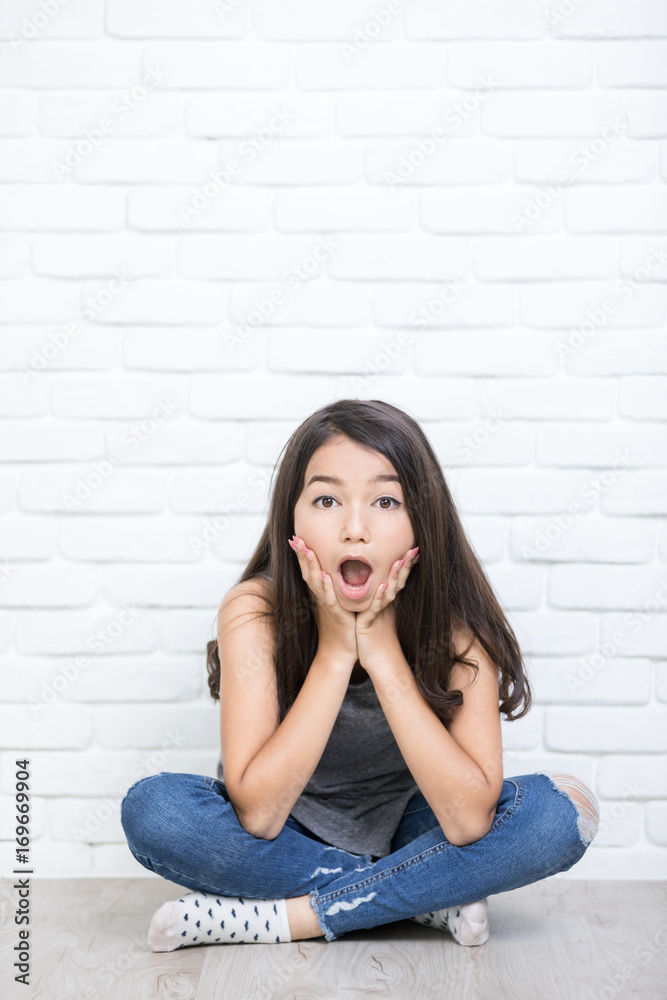 Portrait of a beautiful surprise girl sitting on the floor . Portrait of a beautiful surprise girl sitting on the floor .