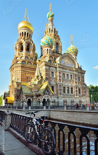 A Bicycle chained to the Bank of the Griboyedov canal embankment on the background of the Church of the Savior on Blood