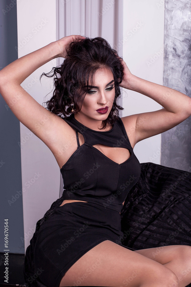 Young woman with her hands behind her head, red lips and curly hair posing for camera. Young woman with her hands behind her head, red lips and curly hair posing for camera.