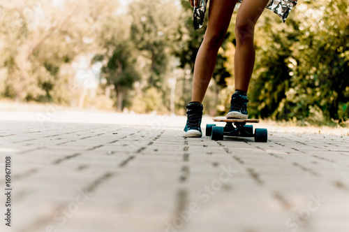 Closeup legs of girl riding modern skateboard on city street