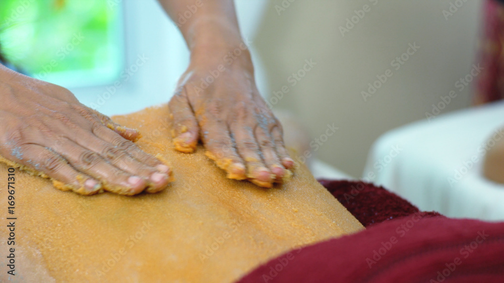 The spa therapist used scrup salt orange on back woman