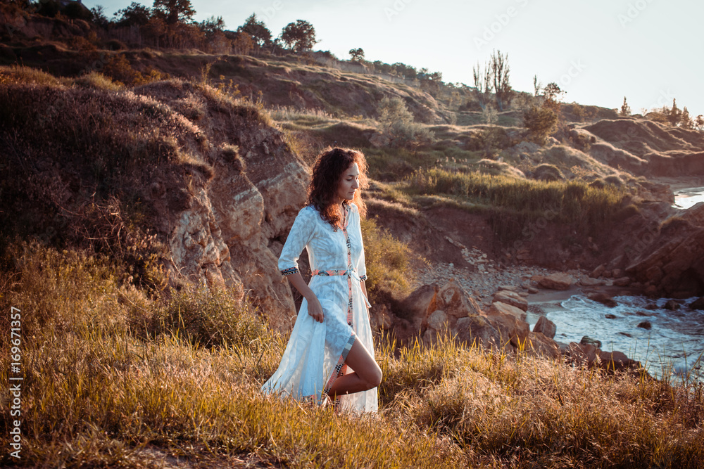 Obraz premium young woman walking on the morning beach in beautiful white dress. Fit female having good time during turing the sunrise.