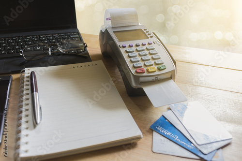 close up cashier use white credit at EDC machine or credit card terminal with laptop background in cashier desk for payment.