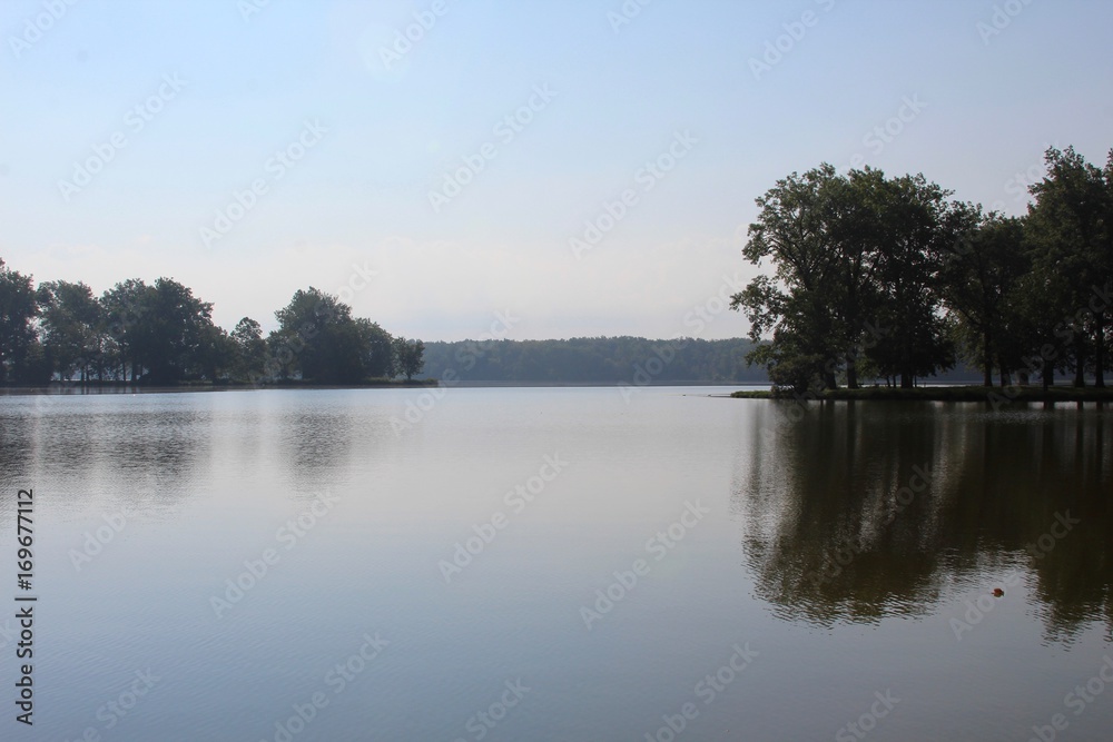 The reflections of the trees off the lake in the morning clear skies.