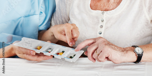 Pflegerin versorgt Seniorin mit Tabletten photo