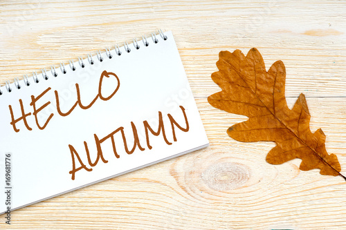 hello autumn message over post card with oak fallen leaf