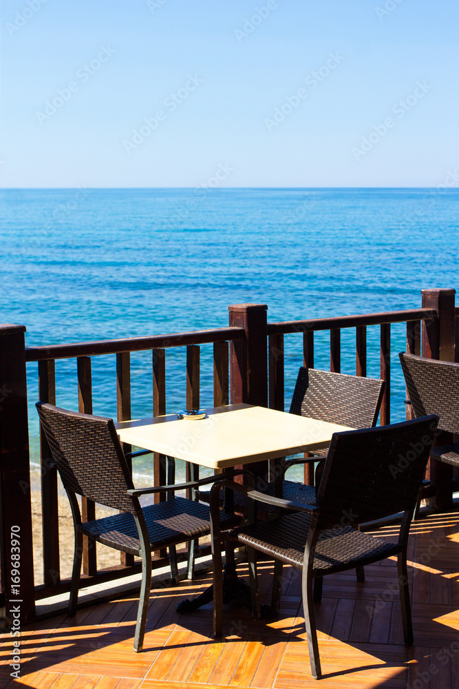 table and chairs on summer terrace with sea view table and chairs on summer terrace with sea view