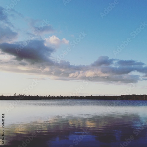 Bog lake at sunset with clouds reflecting in the surface
