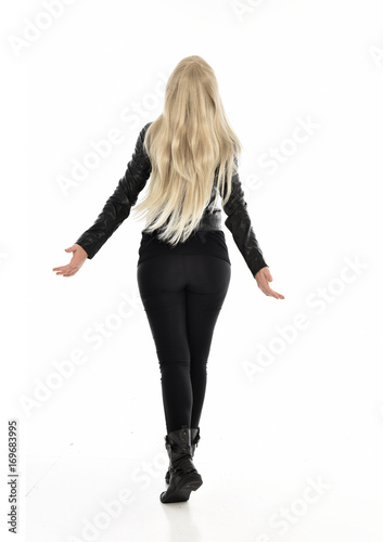full length portrait of blonde girl wearing black leather outfit, standing pose on white background.