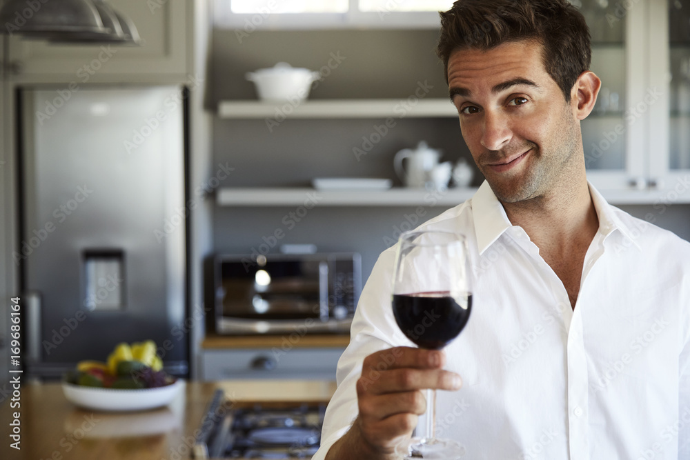 Portrait of guy toasting with red wine in kitchen Portrait of guy toasting with red wine in kitchen
