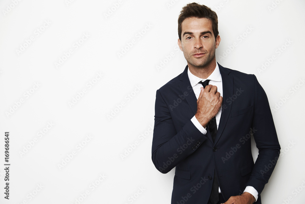 Confident businessman adjusting tie, portrait Confident businessman adjusting tie, portrait