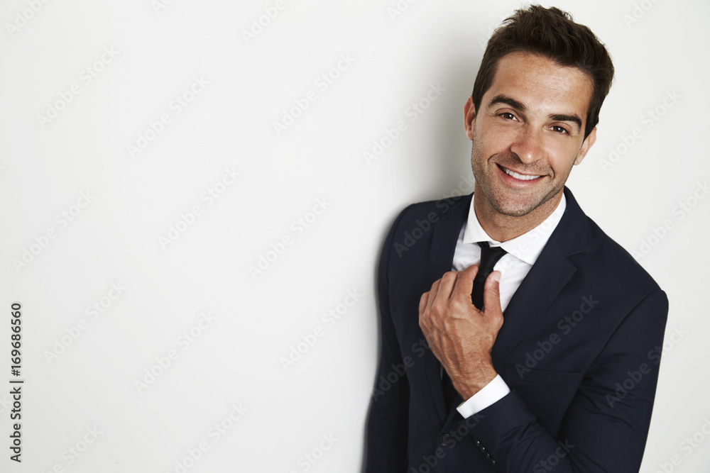 Business guy adjusting tie, smiling in studio Business guy adjusting tie, smiling in studio