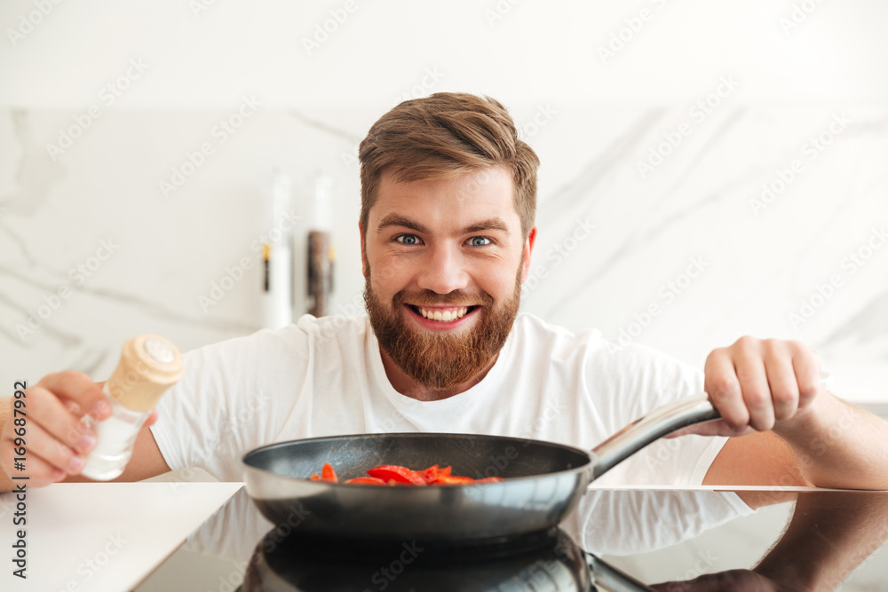 Smiling bearded man sprinkle with condiments of vegetables Smiling bearded man sprinkle with condiments of vegetables
