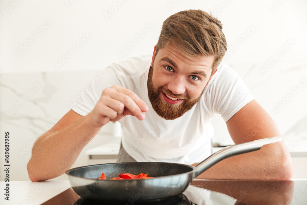 Happy bearded man sprinkle with condiments of vegetables Happy bearded man sprinkle with condiments of vegetables