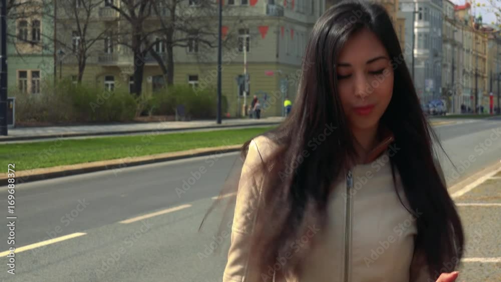 A young Asian woman dances in a street in an urban area