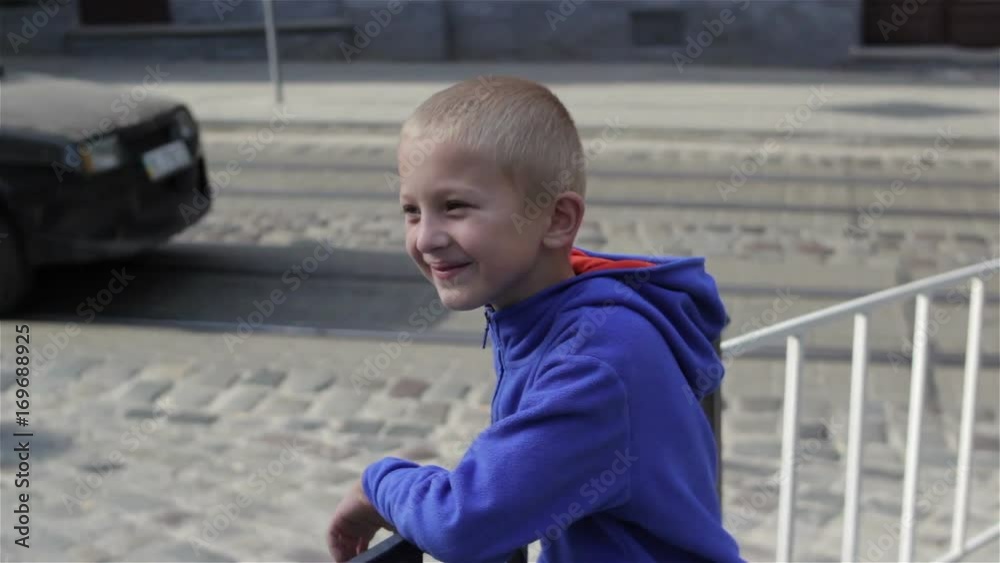 boy looked at the road/boy watches the cars on the road in the city streets boy looked at the road/boy watches the cars on the road in the city streets