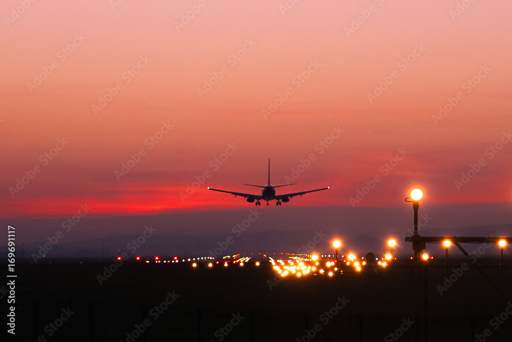 Plane lands at an airfield on the background of red clouds