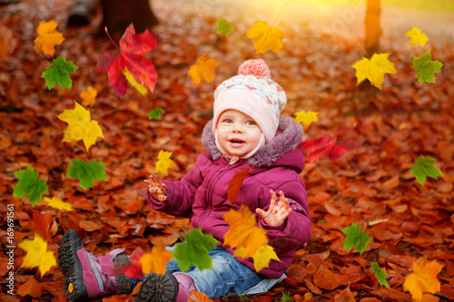 baby girl playing with autumn leaves