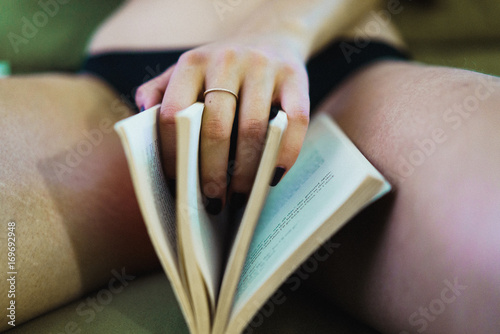 Crop woman with book between legs photo