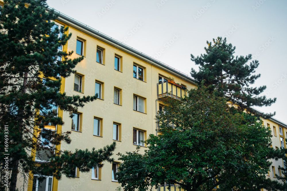 yellow apartment house inbetween of green trees