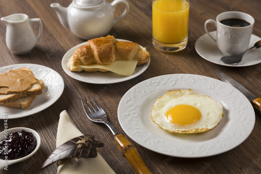 Breakfast Table, Lifestyle / Table with breakfast: coffee, juice, croissant, toast, peanut butter, yogurt, and fried egg 