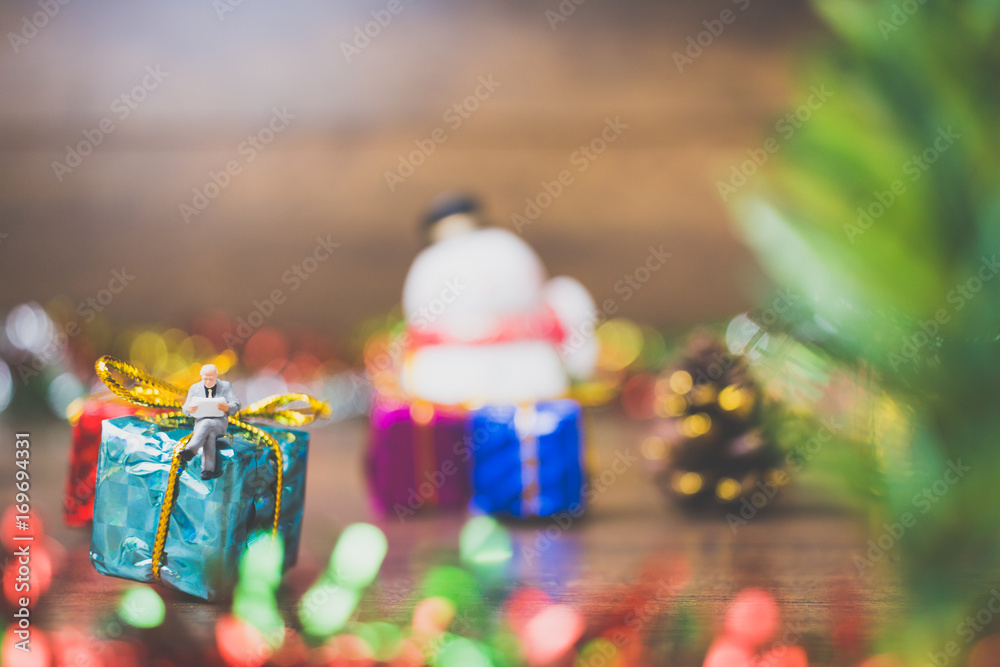 Miniature people on gift box with Christmas Day celebration background