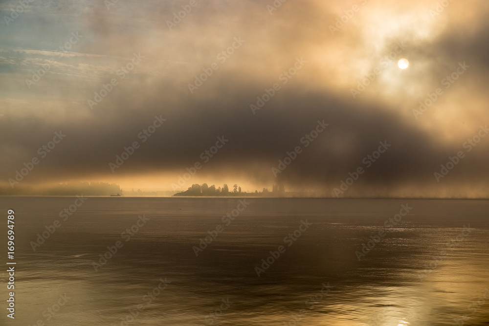 River in the fog, just before sunrise.Warm glow in the clouds from the first sunrays.