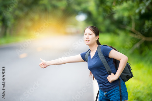 Travel woman with backpack hitchhikers wayside with a happy face