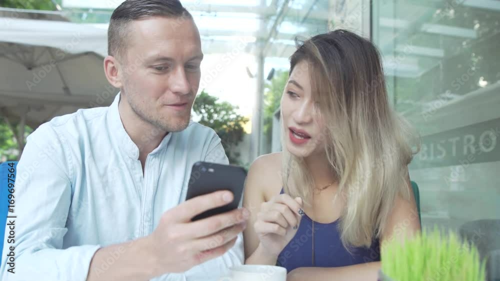 Multicultural couple using app on smartphone together Multicultural couple using app on smartphone together