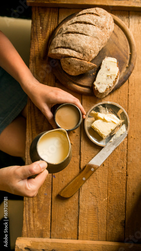 Top view woman has breakfast adds milk to coffee