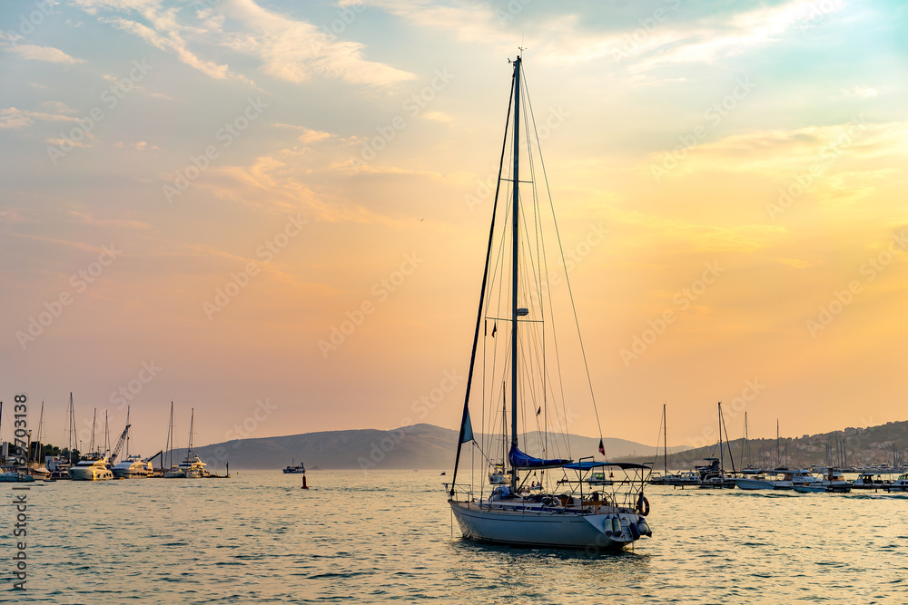 Yacht at Adriatic sea bay at sunset in golden tones. Trogir, Croatia.