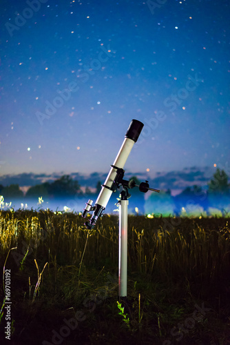 A picture of telescope pointed at the beautiful starry sky with mystery light. Stars on blurred background.