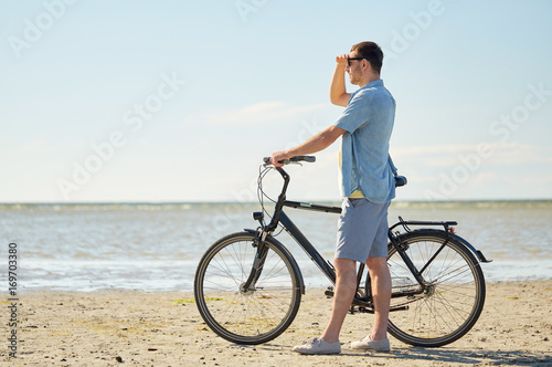 happy young man with bicycle on beach 