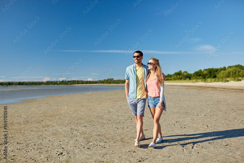 happy couple walking along summer beach