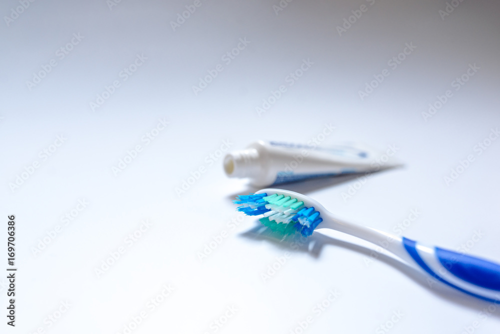 Toothbrush with toothpaste next to a tube of toothpaste against white background Toothbrush with toothpaste next to a tube of toothpaste against white background