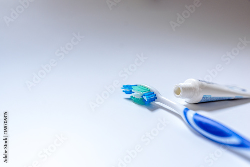  Toothbrush with toothpaste next to a tube of toothpaste against white background