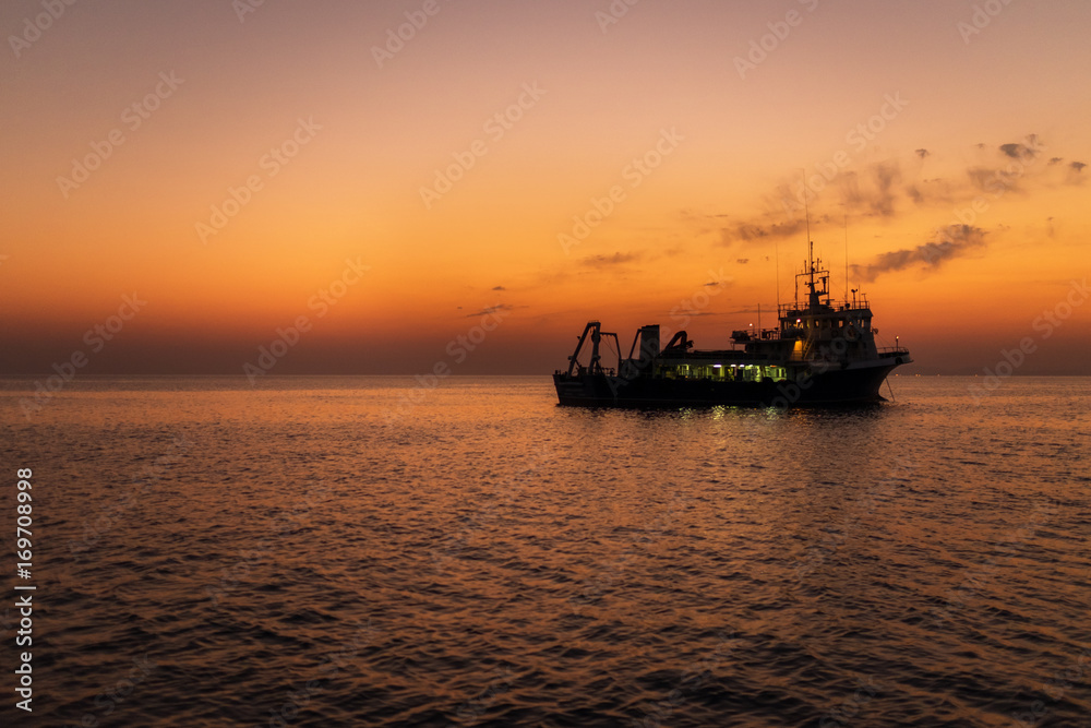 Fishing boat in sea at sunset