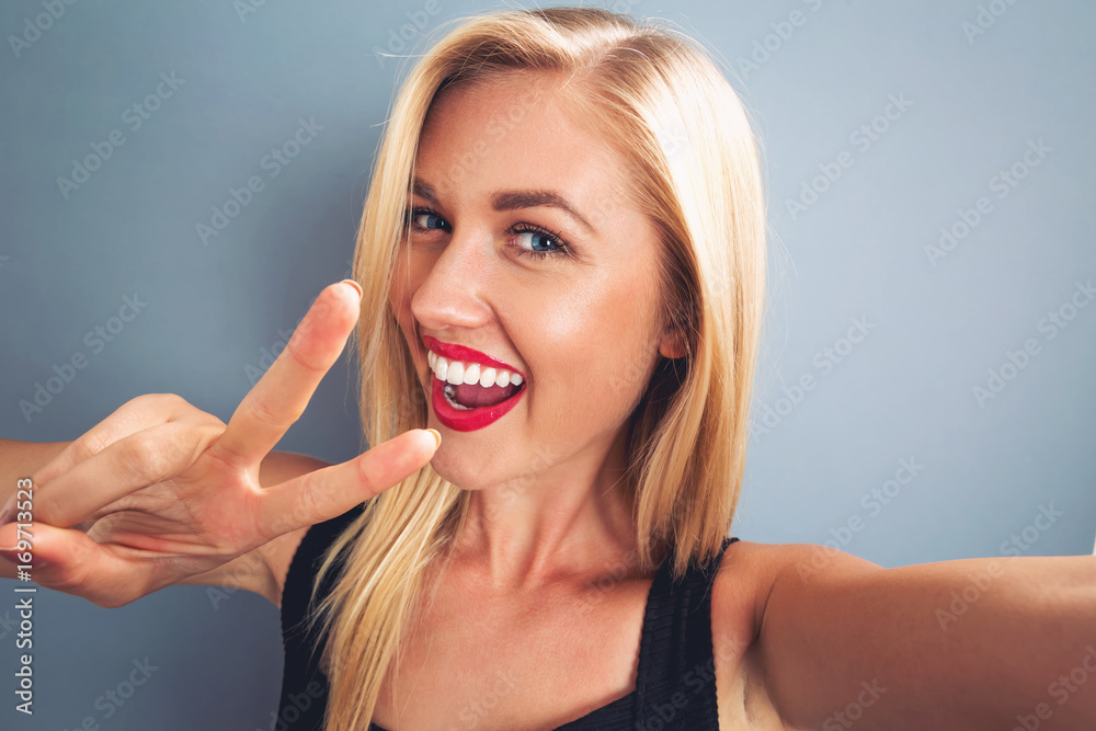 Young woman taking a selfie on a gray background Young woman taking a selfie on a gray background
