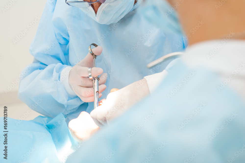 Close up dental surgery process - Implantation. Dentist surgeon with assistant in modern clinic. Stomatology and health care concept. selective focus. Space for text