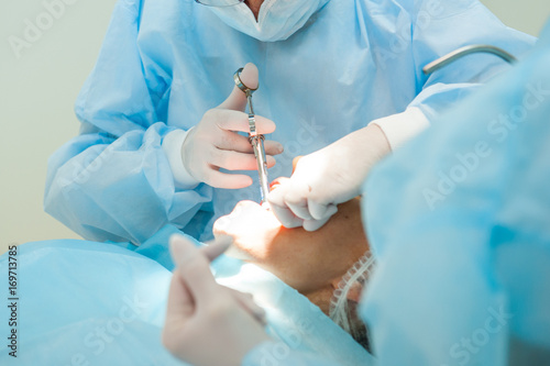 Close up dental surgery process - Implantation. Dentist surgeon with assistant in modern clinic. Stomatology and health care concept. selective focus.
