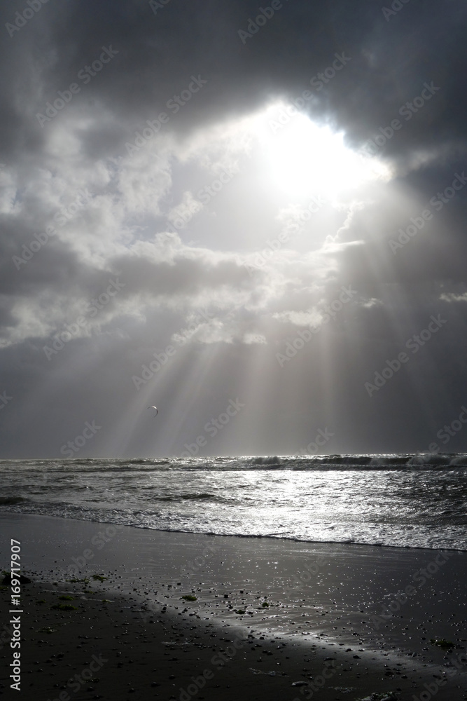Sonnenstrahlen durchbrechen Regenwolken am Meer