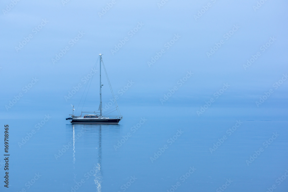 Black yacht in the ocean before sunrise, in the blue twilight hour, reflections in the water. HDR-Photo