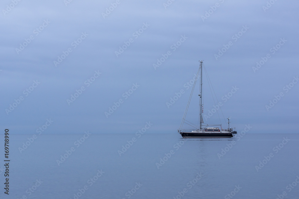 Sailing boat in blue twilight hour, alone in the ocean
