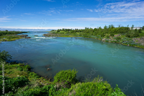 Iceland - Turquoise water of river between green plants flowing into the ocean photo