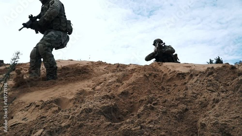 Military soldiers with weapons fighting in desert. Soldiers running on sand